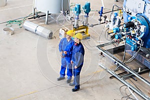Two workers in industrial factory discussing
