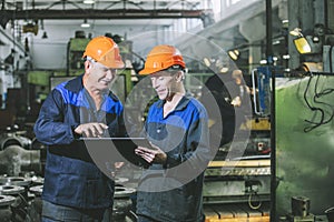 Two workers at an industrial plant with a tablet in hand, workin photo