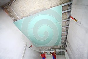 The two workers install the ceiling profile in the photo