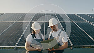 Two workers with a laptop discuss the installation and efficiency of solarpanels