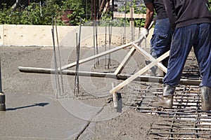 two workers leveling fresh concrete slab with a special working