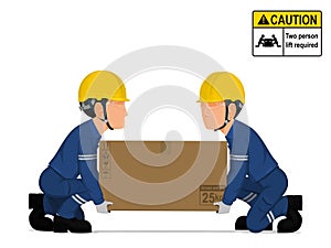 Two workers is lifting a big box on the floor