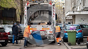 Two workers loading mixed domestic waste in waste collection truck from town