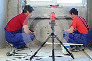 Two workers makes measurements with laser level