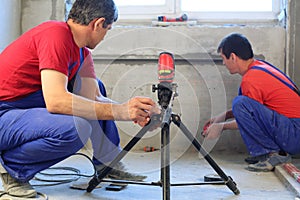 Two workers makes measurements with laser level