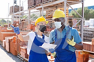 Two workers in masks keep track of the number of redbricks