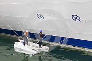 Two workers paint board of cruise liner photo