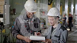 Two workers are in the production hall with large lathes.