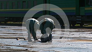 Two Workers In Protective Clothes Rolling Water