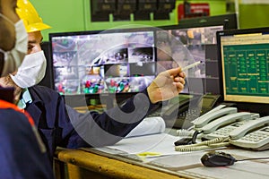 The two workers in protective masks and yellow helmets in control panel in the laboratory