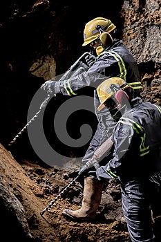 Two workers in protective suit using drill machines