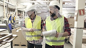 Two workers in reflective waistcoats and helmets at the furniture factory