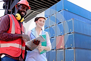 Two workers with safety helmet at logistic shipping cargo containers yard. African engineer man using digital tablet to report