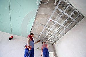 The two workers set the ceiling profile in the new photo