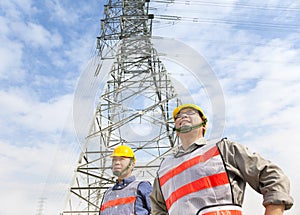 Two workers standing before electrical power tower