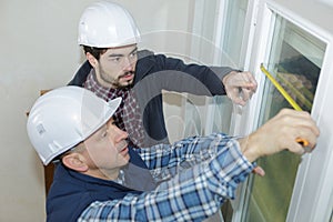 Two workers taking measurements windows