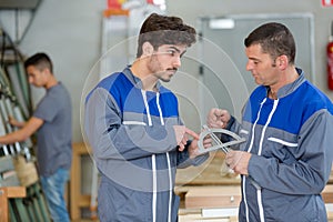 Two workers talking while holding ruler