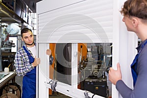 Two workers in uniform inspecting windows with shutter