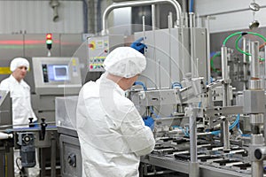 Two workers in uniforms at production line in plant