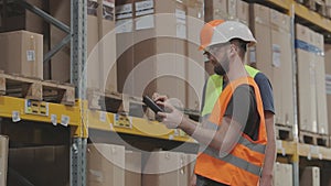 Two workers in a warehouse are discussing work. Engineers in a factory warehouse