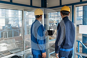 Two workers wearing hard hats while using a tablet PC