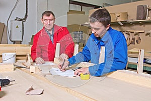 Two workers at a wooden workbench photo