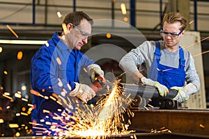 Two workers working with angle grinder