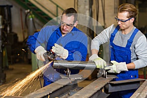 Two workers working with angle grinder