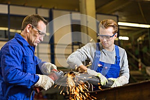 Two workers working with angle grinder