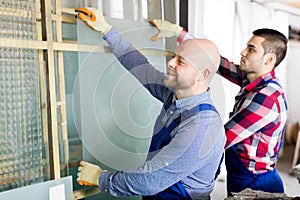 Two workers working with glass