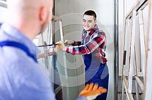 Two workers working with glass