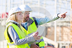 Two workers working outside with a tablet on a construction site