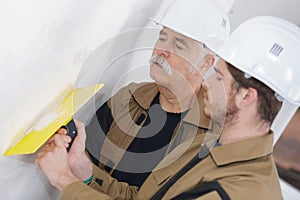 two working builders plastering wall