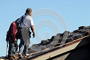 Two workmen walking on roof of building