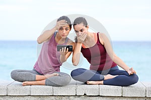 Two worried yogis watching difficult online yoga class photo