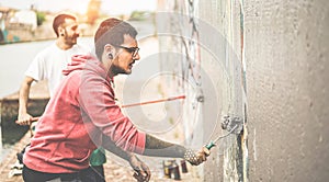 Two writers covering the wall with grey color before painting their picture - Contemporary artists at work - Urban lifestyle,