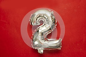 Two year birthday. Number 2 foil balloon isolated on red background