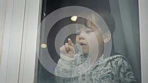 A two-year-old Azait boy looks out of the window, emotionally points his finger down
