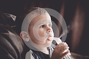 Two year old boy making inhalation with nebulizer at home