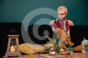 A two-year-old child with curly blond hair stands on a sofa.