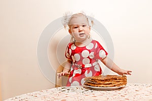 Two-year-old girl and a large plate of pancakes. Maslenitsa holiday. pancakes and children