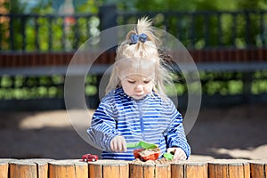 Two year old girl playing sand in the sandbox