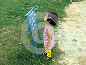 Two year old girl reading a sign board