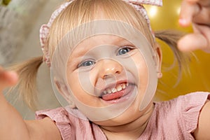 Two-year-old girl smiling looking at the camera, sticking out her tongue, drooling in children, teething.