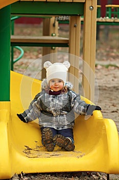 Two year old happy girl sliding on a winter playground