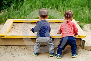 The two-year-old twin brothers play together on the playground.
