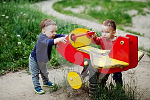 The two-year-old twin brothers play together on the playground.