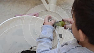 Two years old boy playing with dirt from the white bucket