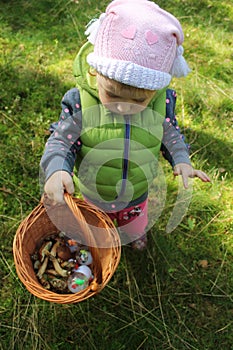 Two years old girl with a basket full of mushrooms
