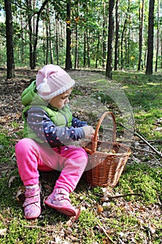 Two years old girl with a basket full of mushrooms